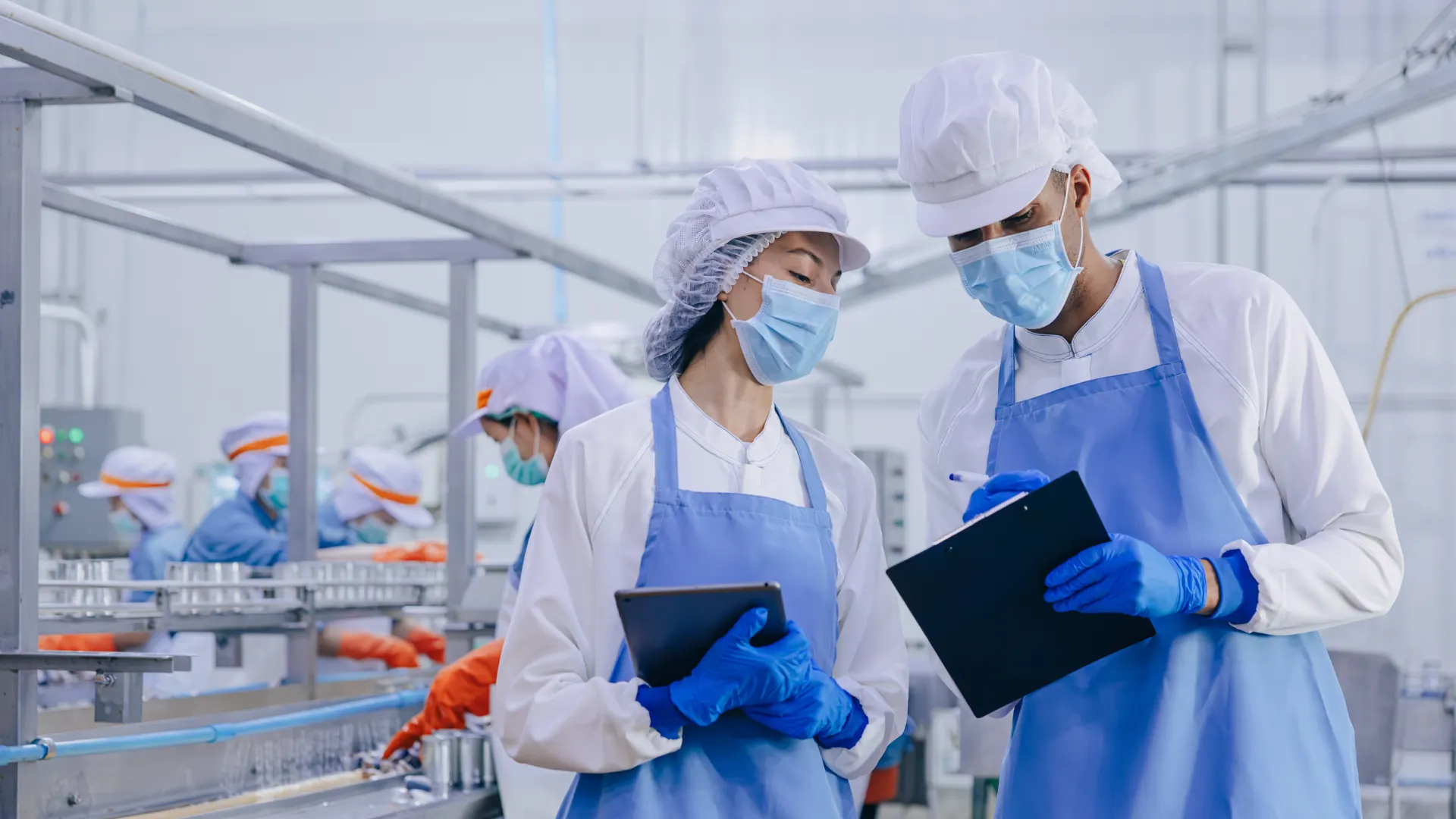 Two food safety inspectors with a clipboard and tablet in a food production facility