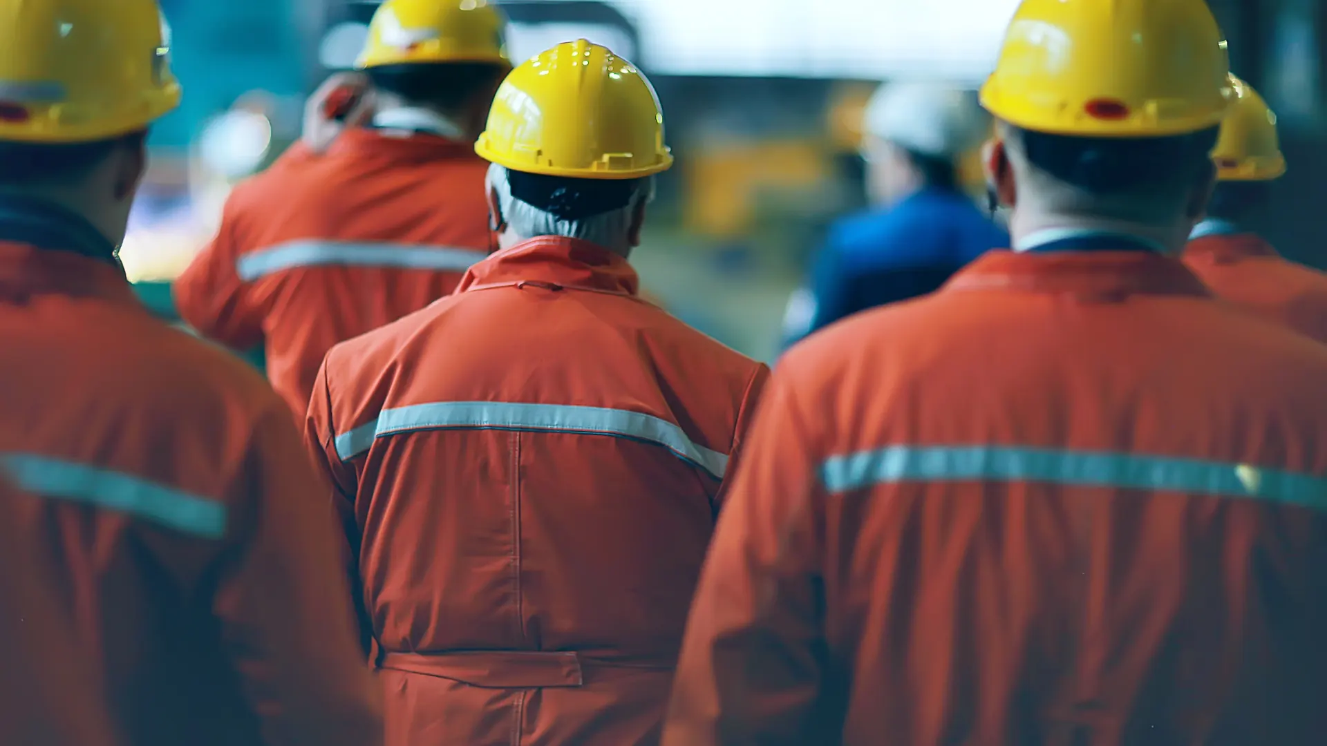 A group of workers in orange coveralls and hard hats on site